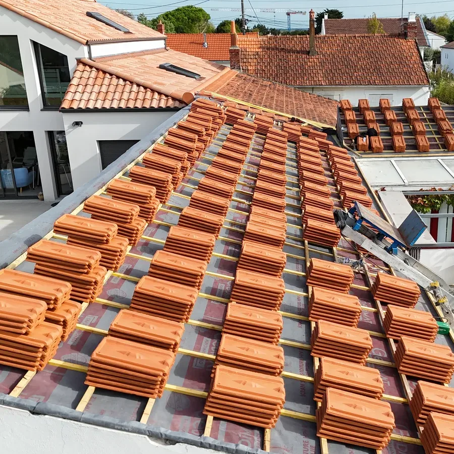Tuiles neuves réparties sur une toiture en cours de réfection par Matel Couverture