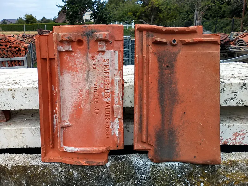Tuile en terre cuite devenue poreuse, marquée de traces blanchâtres